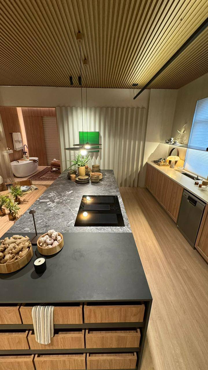 Cozinha contemporânea com ilha em porcelanato claro e pendentes metálicos.